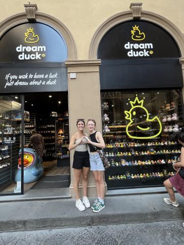 Two women pose while making an Oregon "O" shape in front of a Dream Duck Store