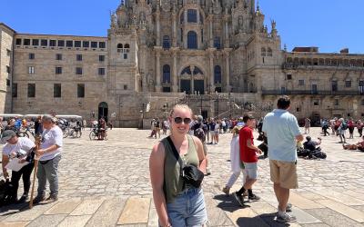 A young woman stands in front of an ornate building