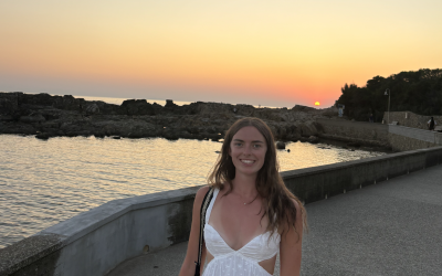 A young woman standing in front of a sunset in Italy