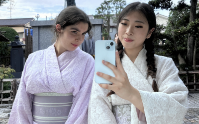 Two college-aged girls taking a mirror selfie dressed in traditional Japanese clothing.